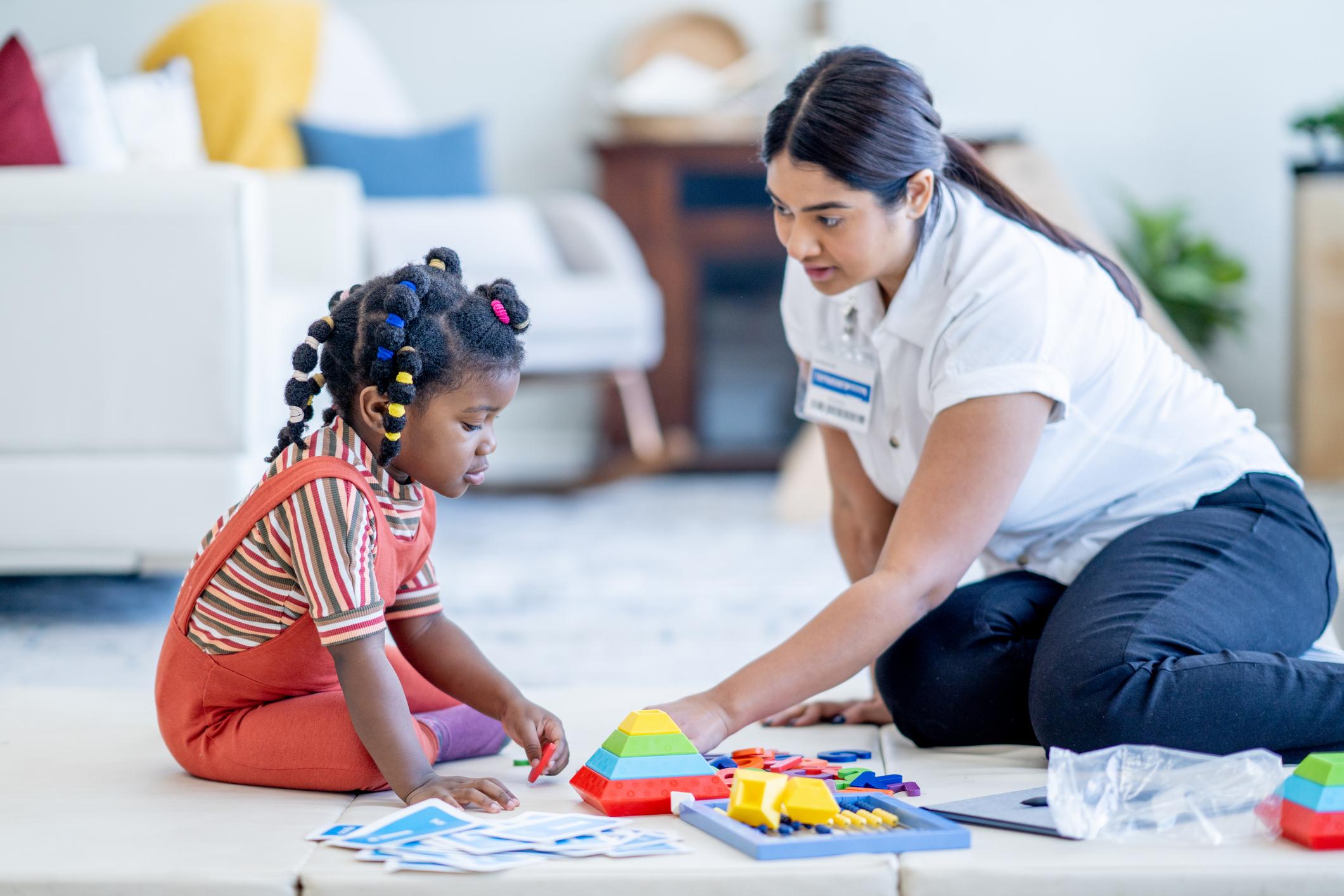 woman helping child with occupational therapy